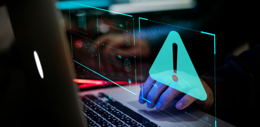 Man typing on keyboard with warning triangle overlay.
