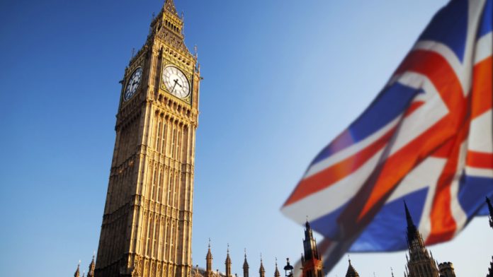 Big Ben in London next to UK flag.