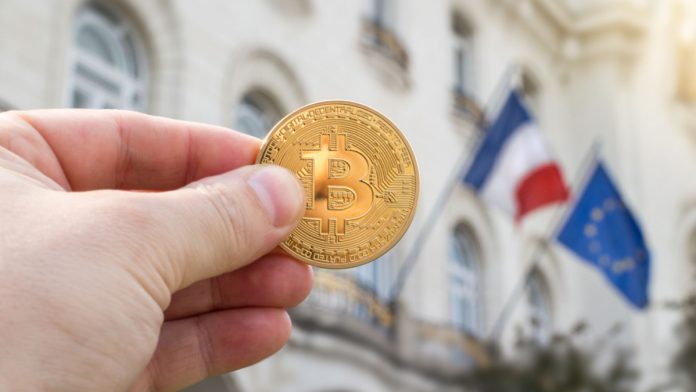 Hand holding golden Bitcoin against flags of France and European Union