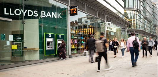 People walking past a retail branch of Lloyds Bank.