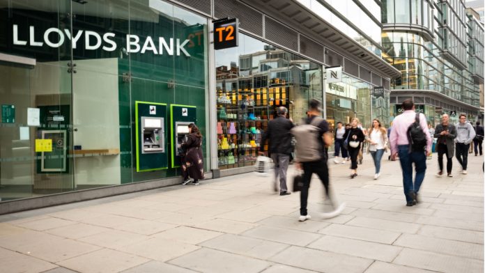 People walking past a retail branch of Lloyds Bank.