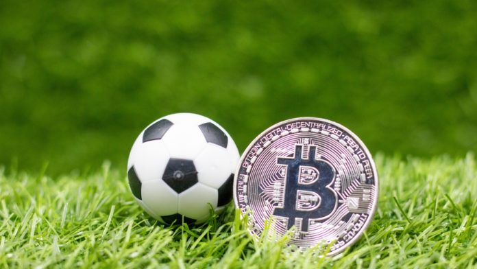 Soccer ball with bitcoin are on green grass for sport betting concept.