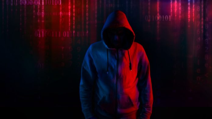 Hooded hacker with code background security concept.