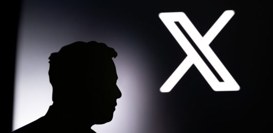 CALIFORNIA, USA, 24. JULY 2023: New logo of Twitter. Silhouette of Elon Musk in front of black banner with Twitter new X logo in background.