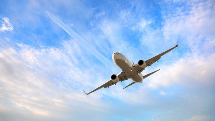 White passenger airplane flying in the sky amazing clouds in the background - Travel by air transport.