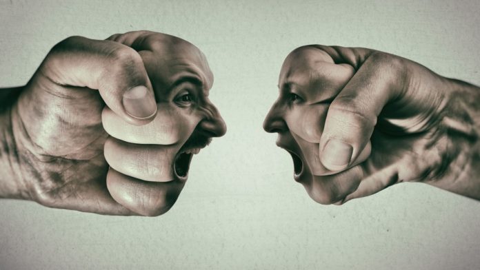 Two fists with a male and female face collide with each other on light background. Concept of confrontation, competition, family quarrel etc.