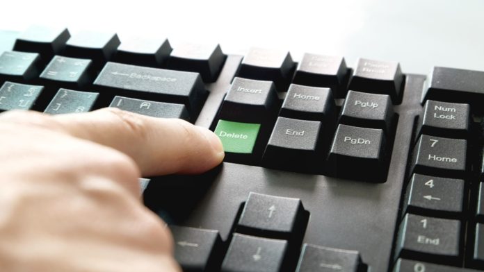 Photo of male hand pressing Delete.