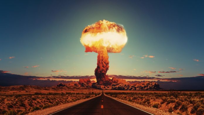 Asphalt road goes to a nuclear explosion. Terrible atomic explosion of a nuclear bomb with a mushroom cloud of radioactive dust. Hydrogen bomb test. Nuclear catastrophe. Way to nuclear war.
