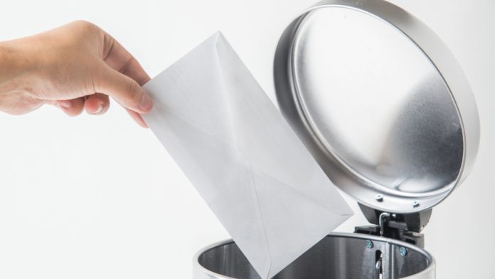 A person placing a letter/envelope in a bin.