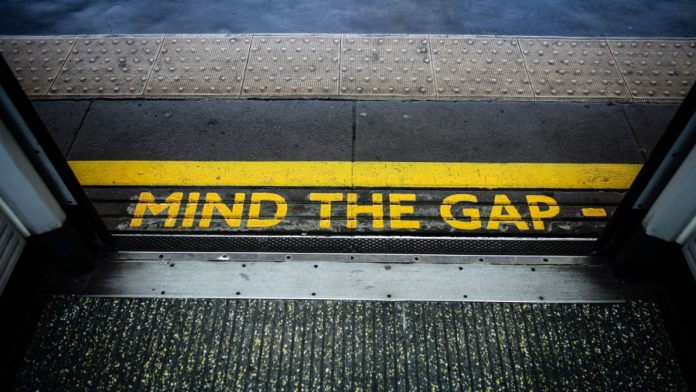 "Mind the gap" printed on the floor of a train platform.