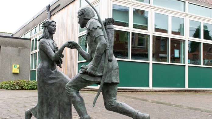 Statue of Robinhood proposing to Maid Marian on bended knee, holding hands, Edwinstowe, Sherwood Forest.