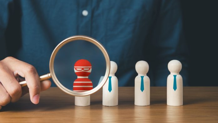 business protection, cybersecurity, cybercrime and hacker concept.businessman holding magnifier and searching wooden of thief hacker in business team.