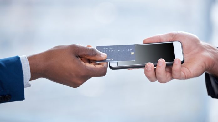 Man using Apple's Tap to Pay by placing his contactless card on a mobile phone.