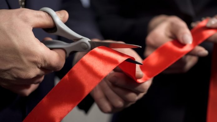 Business man cutting red tape with scissors.