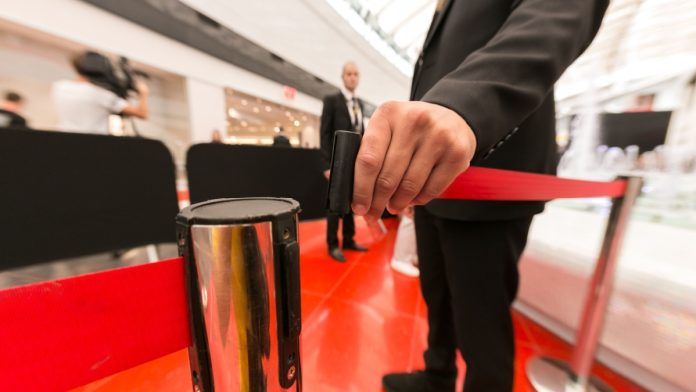 Security hand fastens a red tape closing the passage.