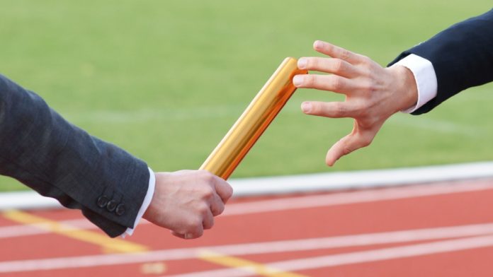 Businessman passing baton in relay race.