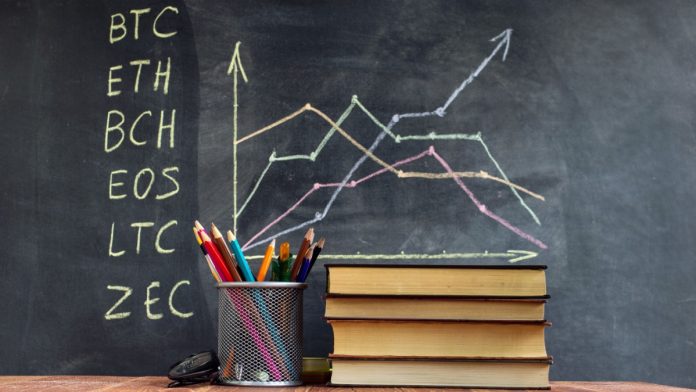 A table with books on the background of graphs on a chalkboard. Learning crypto currency in school. Concept, a new educational subject for children.
