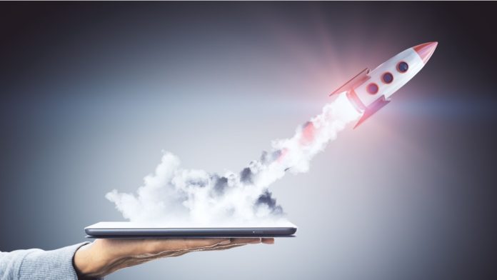 Hand holding smartphone with launching rocket on dark background. Startup and technology concept.