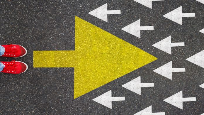Different thinking and Business and technology disruption concept. Yellow big arrow opposite direction with white arrow on road asphalt. Standing out from the crowd.