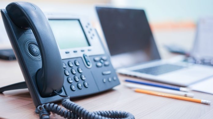 close up soft focus on telephone devices with notebook stationary at office desk with light effect,communication technology concept.