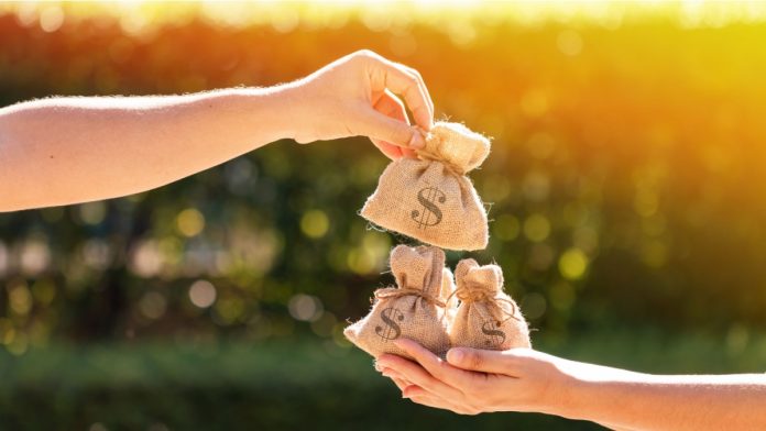 A man and a women hands hold a money bags in the public park for loans to planned investment in the future concept.