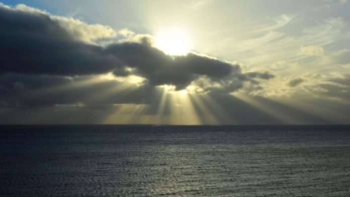 Conceptual sunset, with the sun blown out against a low key foreground. The spiritual and uplifting supernatural effect, of natural sun rays shining through the clouds.