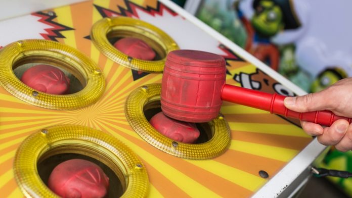 A person playing a game of 'Whack a Mole'.