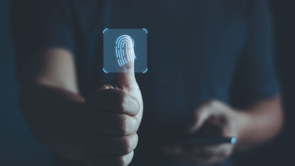 A man holding out his hand and pressing his thumb into the lens to show a fingerprint, representing the latest in payment security