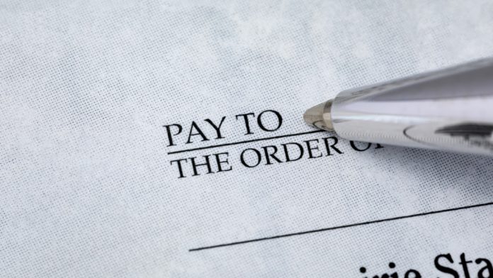 Writing check with pen. Banking, paying bills, and financial fraud concept.