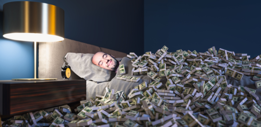 Man in bed covered with stacks of cash, representing embedded finance.