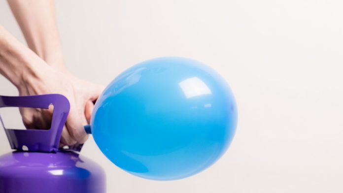 A young guy inflates a balloon with helium, representing Elantil's expansion into payments