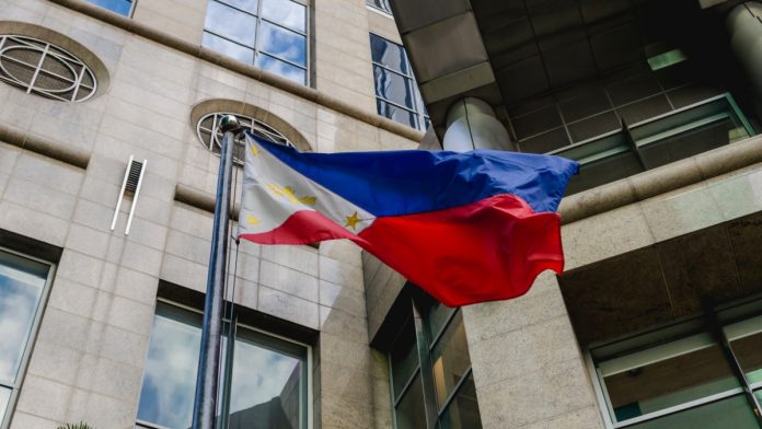A Philippine Flag waves in the wind in front of a corporate office building in Makati, Philippines.