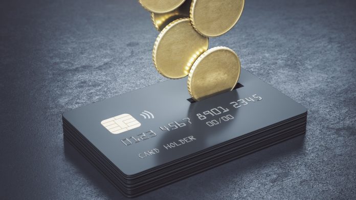 Cashback loyalty programm concept with metal money coins bound for a stack of black credit cards on abstract dark surface. 3D rendering