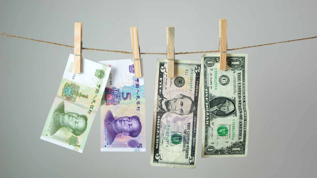 US dollar and China Yuan banknotes hanging on rope for Chinese money laundering concept