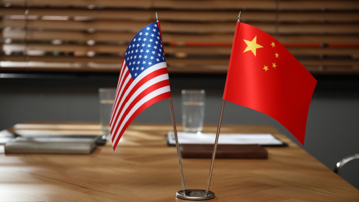 USA and China flags on wooden table in office. International relations.