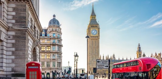 Red telephone box and double-decker bus on Parliament square and Big Ben tower, London, UK.