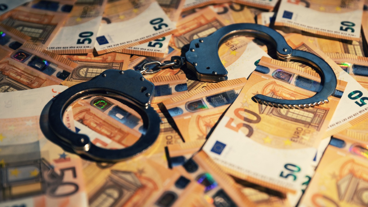 financial crime concept - handcuffs on cash money
