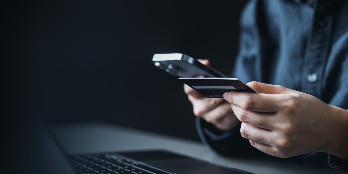 Hands holding a phone and a credit card to illustrate gaming payments.