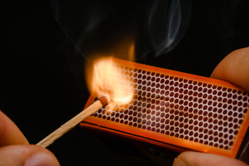 Image of a man lighting a match representing friction