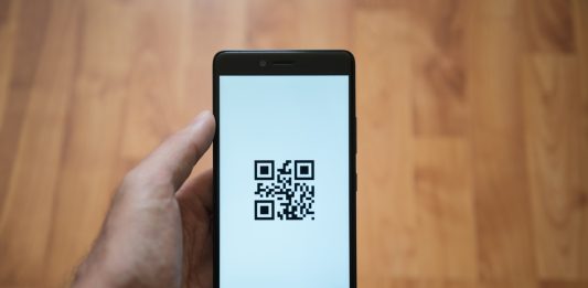 Man holding a phone with a QR code on it