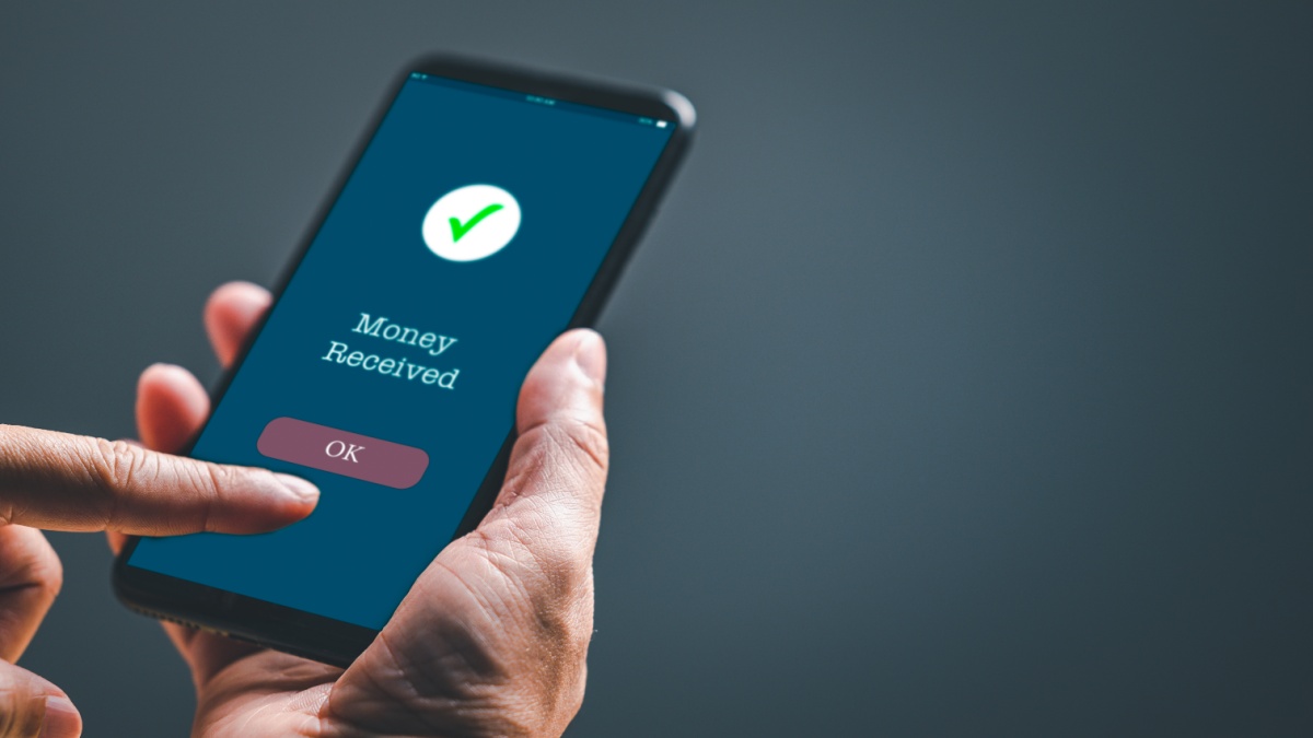 A businessman hand holds a smartphone on the screen with the message money sent transfer Concept. business, banking, financial online transactions with mobile devices.
