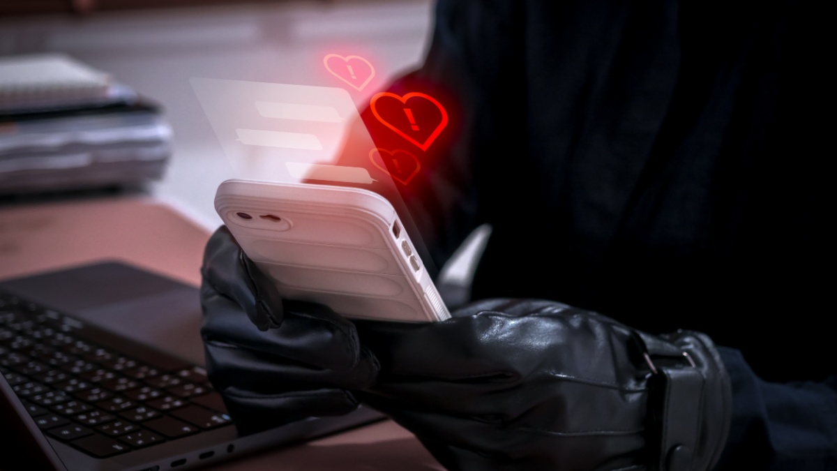 Romance scam concept showing a cybercriminal using a smartphone to deceive victims with fake love messages. Online dating fraud and social engineering risk through chat applications and social media.