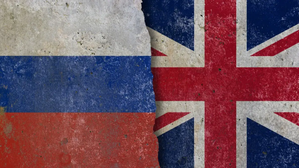 Russia and United Kingdom geopolitical conflict concept with cracked flags wall background.