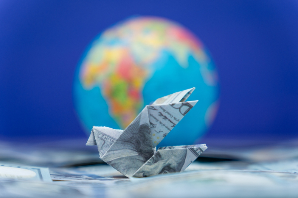 an origami bird made from a US dollar representing cross-border remittance payments